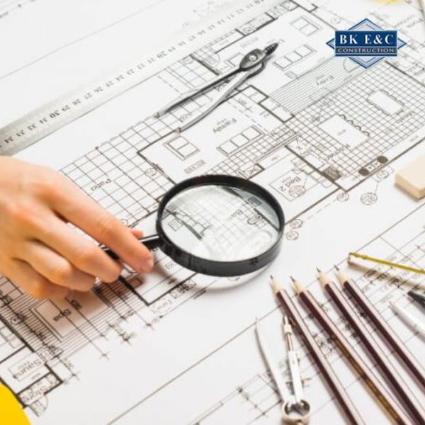 Chuyên gia sử dụng kính lúp kiểm tra bản vẽ kỹ thuật nhằm phân tích số liệu và lập báo cáo kiểm định
